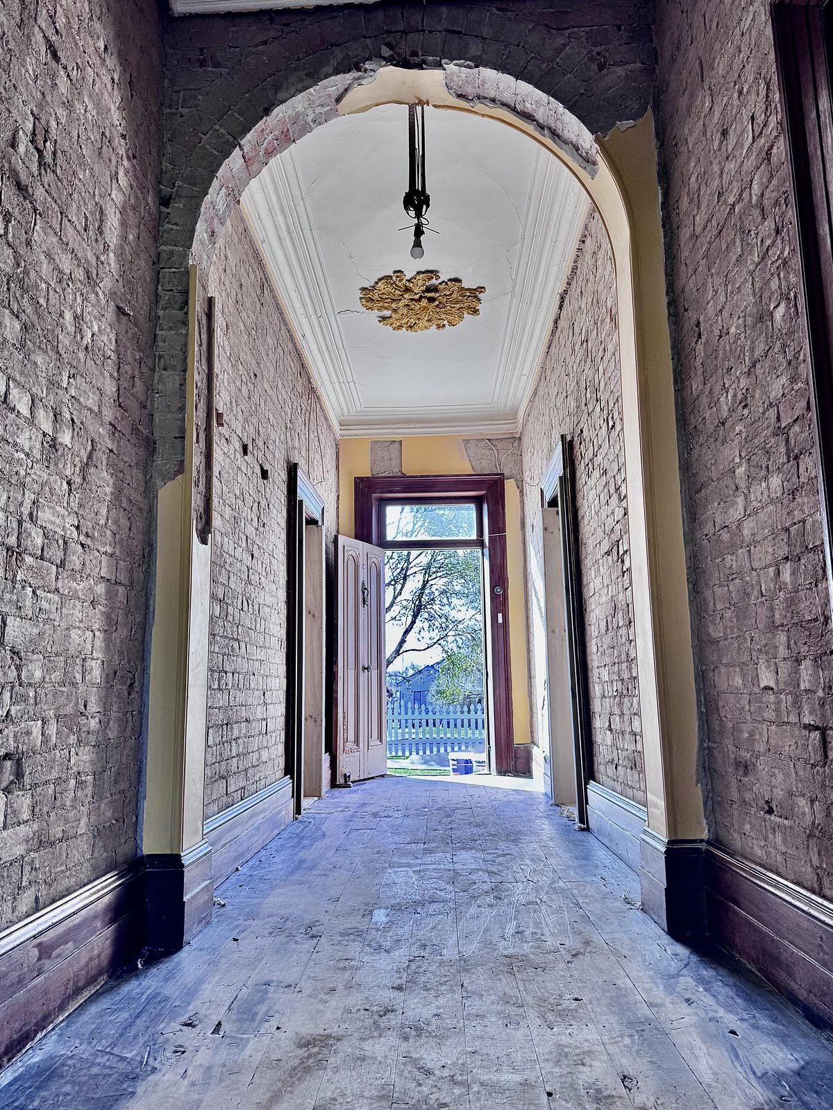 Clarendon: the original hallway stripped back to brick, with the arch and ceiling rose intact